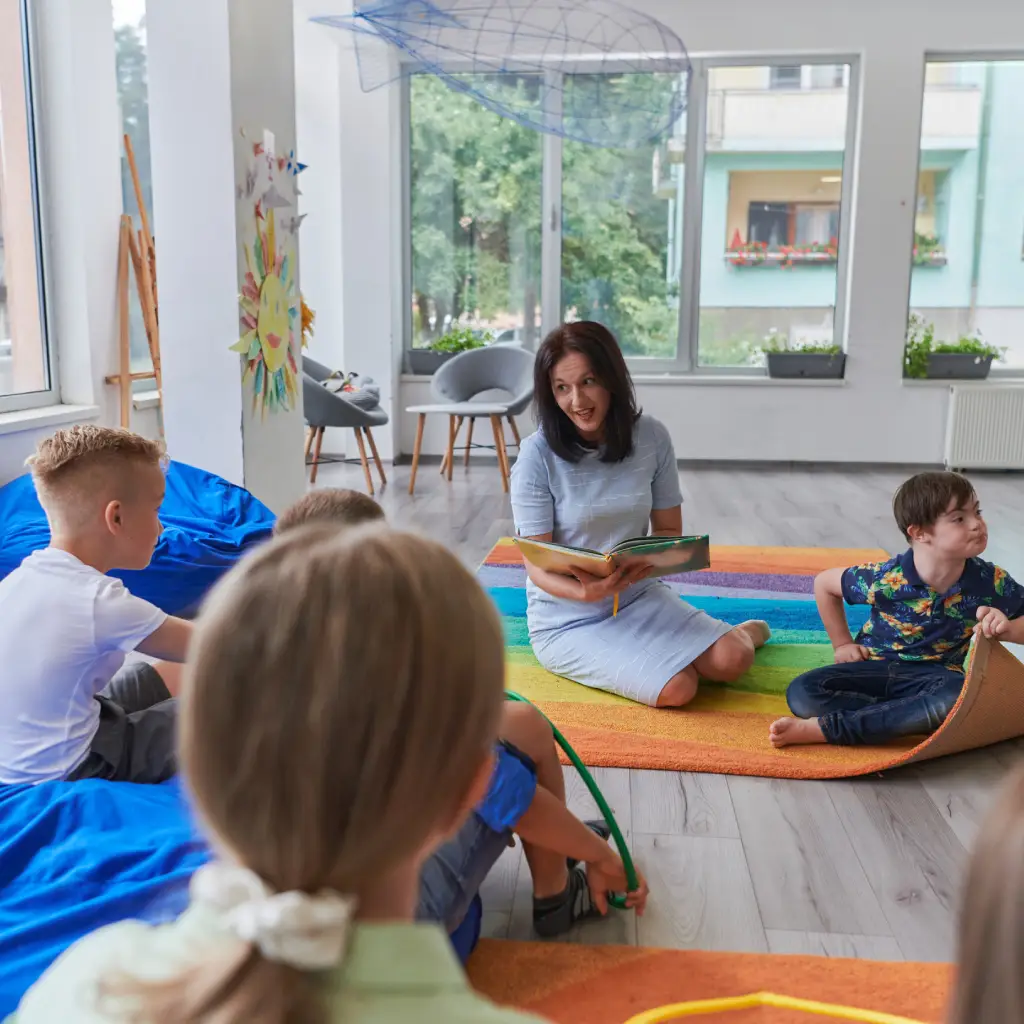 Reading time in an elementary school or kindergarten, a teacher reading a book to children in an elementary school or kindergarten. The concept of pre-school education. Selective focus